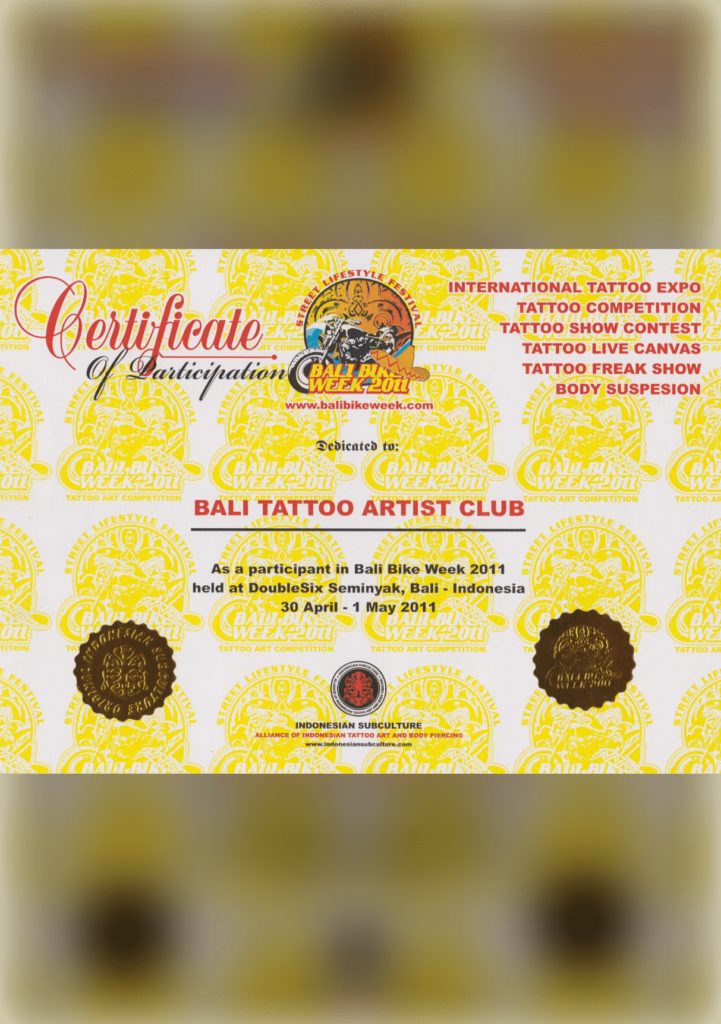 A shimmering, gold-embossed certificate hanging on a bamboo wall, honoring a tattoo artist of East Asian descent as the recipient of the "Golden Needle Award" for their exceptional precision and creativity in Bali's tattoo scene.