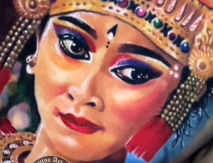 A detailed shot from a tattoo portfolio, focusing on an artist's hands as they create a piece inspired by Balinese culture. The image represents the meticulous attention to detail and cultural reverence in the local tattooing process.